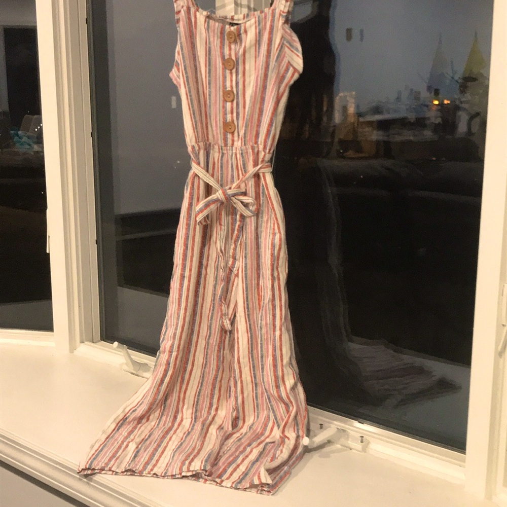 Cream colored jumpsuit with pastel colored stripes, oak buttons and a cloth tie